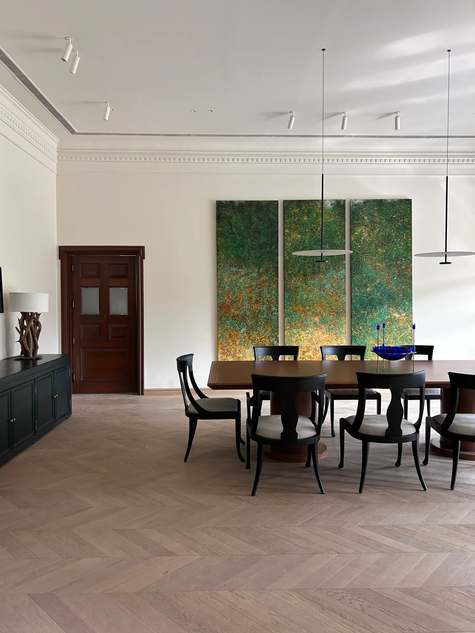Dining room with herringbone floor and a green triptych by Sonia Gehlot
